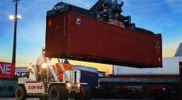 Contêiner sendo erguido por um Reach Stacker da Covre ao entardecer