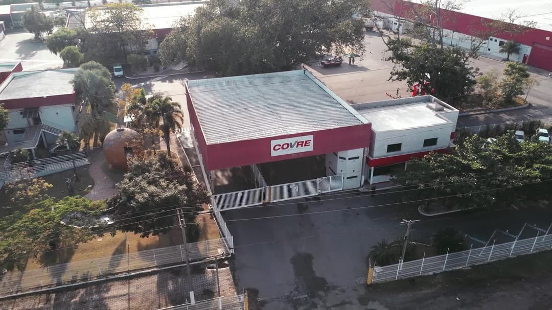 O pátio da matriz da Covre visto do alto, com o prédio vermelho e branco e as carretas