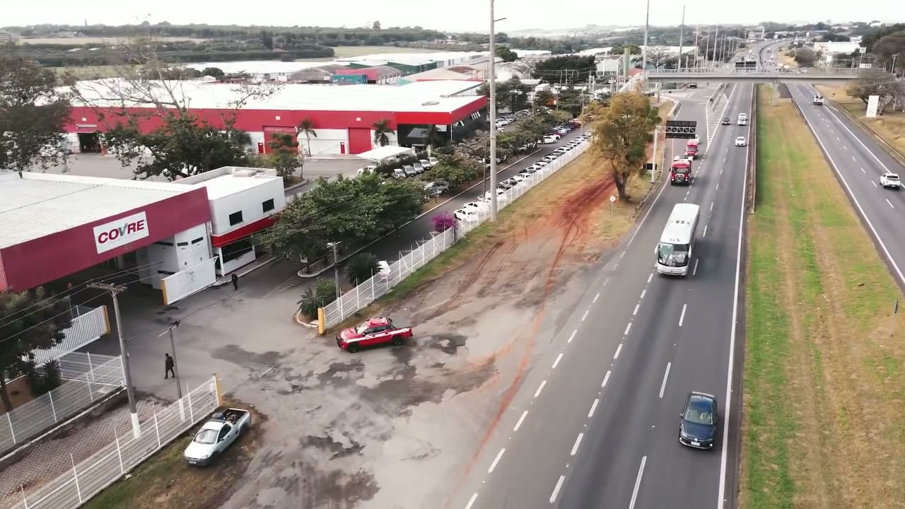 Vista do alto da matriz da Covre, com o prédio vermelho e branco, o pátio e a Rodovia Anhanguera ao lado