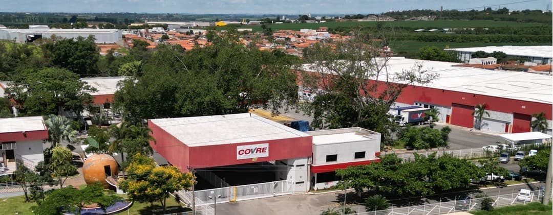 A portaria e os galpões da matriz da Covre vistos do alto, entre as árvores
